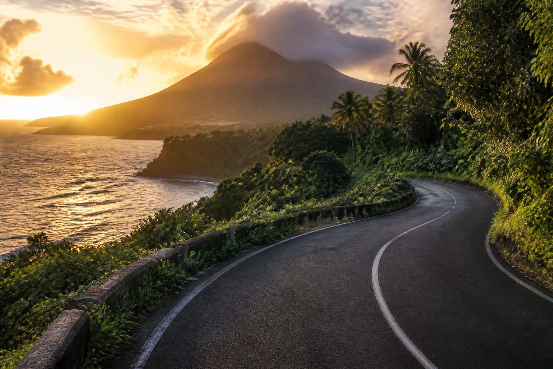 Route côtière tropicale de Guadeloupe au coucher du soleil, avec la silhouette de La Soufrière — FMF Guadeloupe